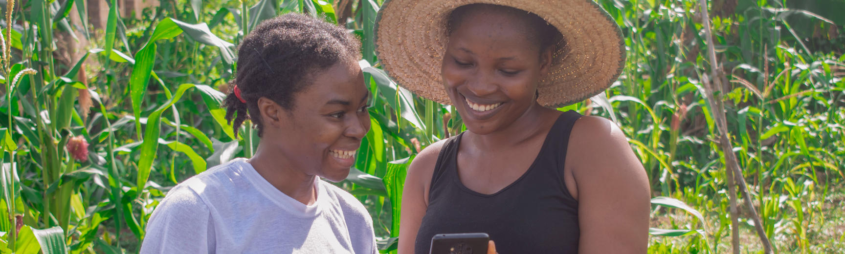 An African woman and teenager look at a phone together outdoors
